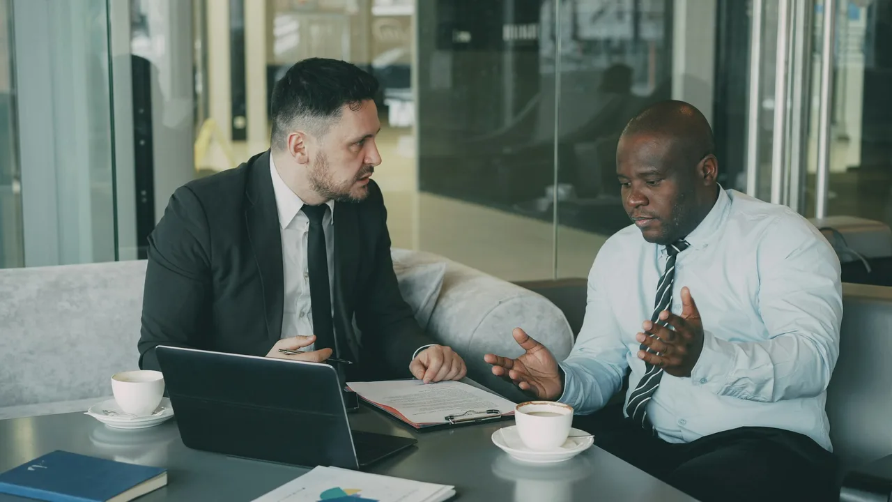 An older executive going over documents with a colleague at a meeting table
