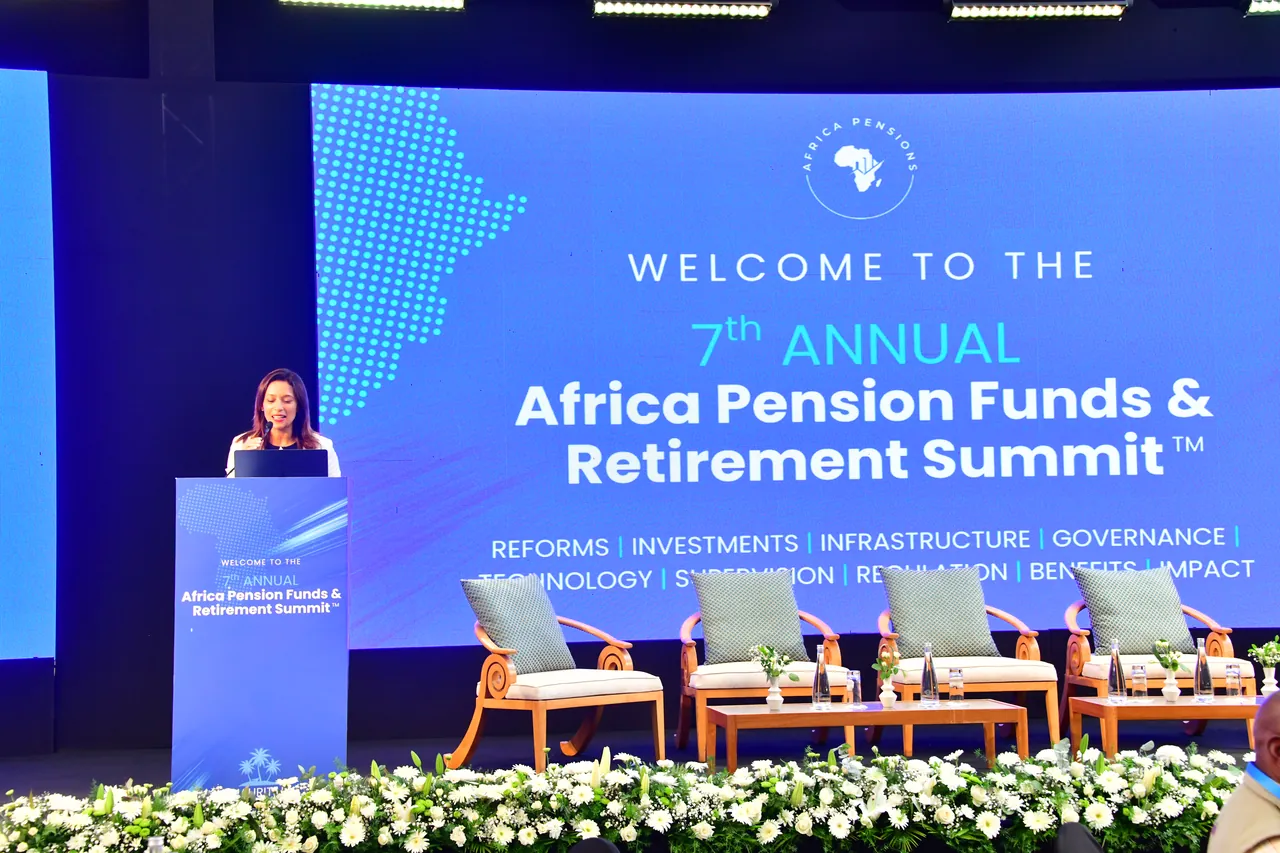 A speaker at the podium beside the summit welcome screen